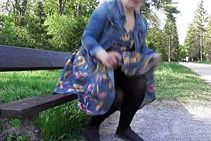A mature woman in a transparent dress showing her hairy pussy in a park